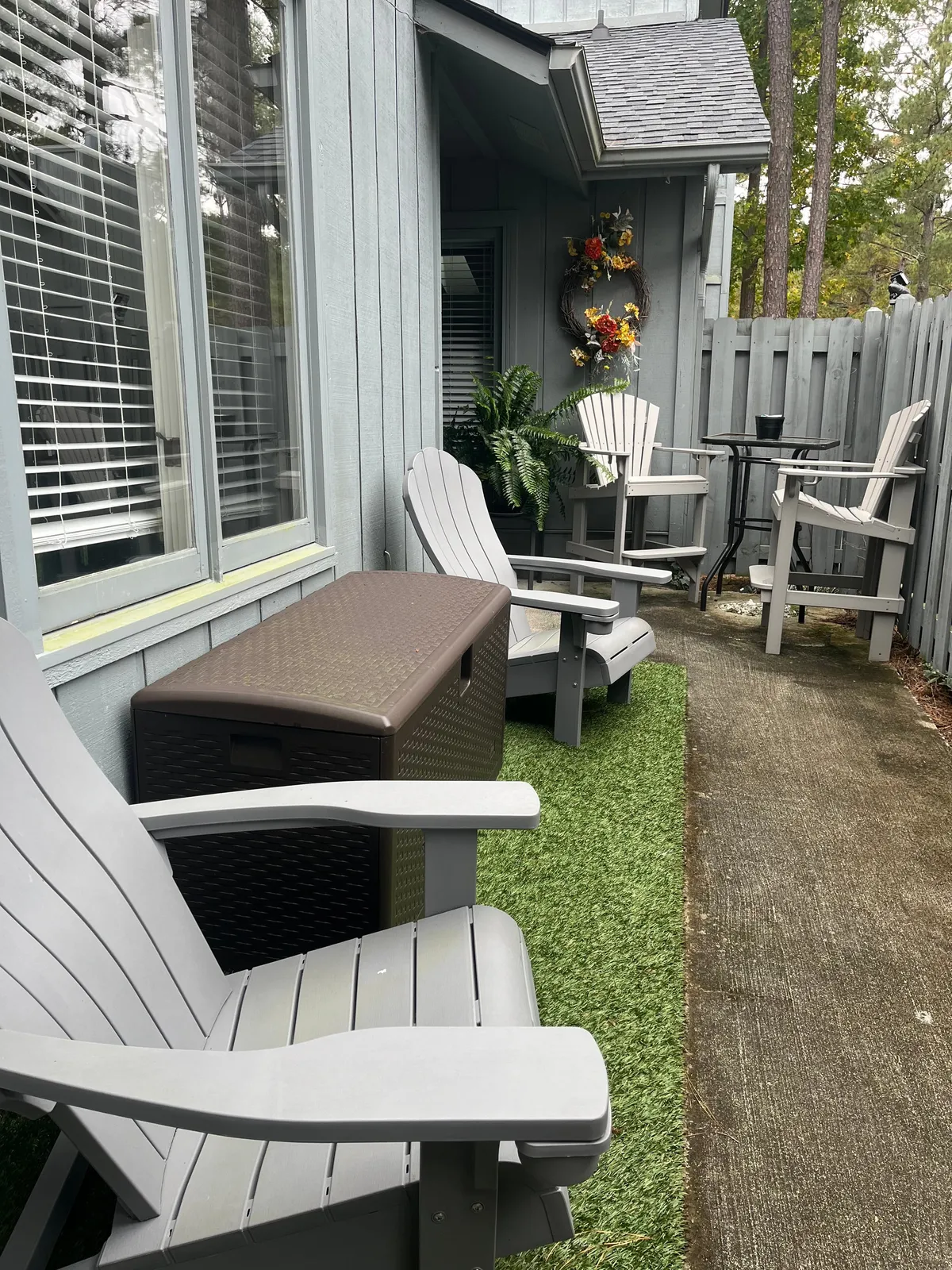 A cozy exterior setting with Adirondack chairs, a storage box, and decorative touches like a wreath and potted plants. The ambiance is calm and welcoming, ideal for relaxing after a day of exploring or riding.