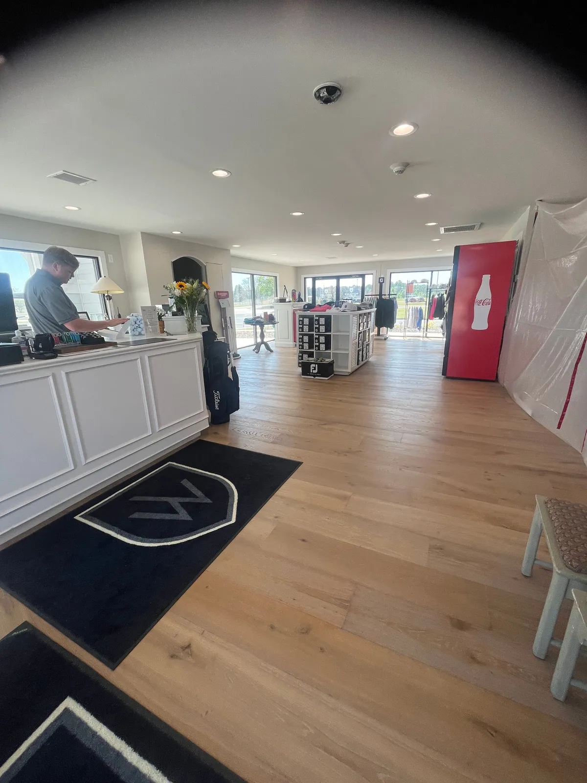 A bright reception area with a welcoming desk, shelves displaying local merchandise, and large windows letting in plenty of natural light. The space is lively, with subtle cues that guests are arriving and being greeted warmly, hinting at the start of an adventure or exploration.